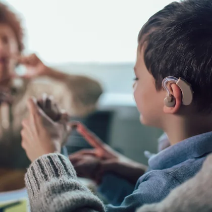 A student wearing a hearing aid in conversation with a classmate.