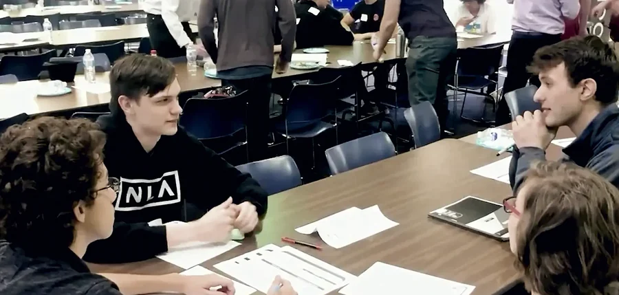 Mentors and students working together around a table at a SharkMakers workshop.