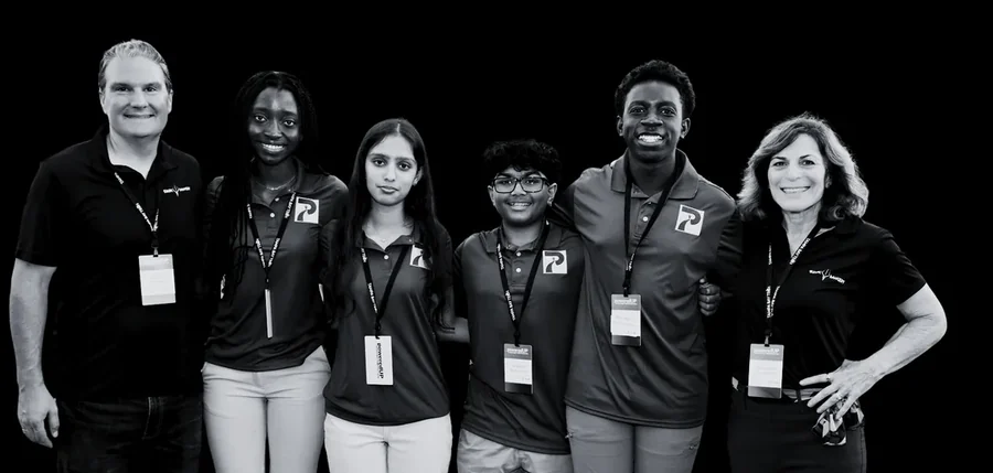 A company team standing with SharkMakers students at a program event.